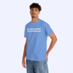 A man poses in the Hey Quick Question Are You Kidding Me Shirt—a light blue tee with bold white text. He has short curly hair, wears casual blue jeans, and stands against a simple light backdrop.