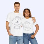 A smiling man and woman stand together, arms around each other, in matching Thank God I'm Gay Shirts featuring a teddy bear and “THANK GOD IM GAY” text on bold, white tees.