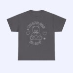 The Thank God I'm Gay Shirt is dark gray and features a teddy bear line drawing with two hearts and flowers. "THANK GOD IM GAY" is printed above and below the bear for a bold look.