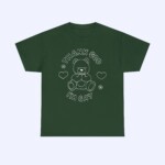 The Thank God I'm Gay Shirt is dark green and features an outline of a teddy bear, hearts, flowers, and the phrase "THANK GOD I'M GAY" in white above and below the design.