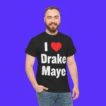 A bearded man smiles against a bright blue background, proudly wearing the I Love Drake Maye Shirt, which features “I ♥ Drake Maye” in bold white letters.