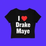 The I Love Drake Maye Shirt is a black crop top with bold white letters and a red heart reading “I Love Drake Maye,” shown on a vibrant purple background—ideal for any fan.